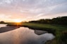 the sun is setting over a small river