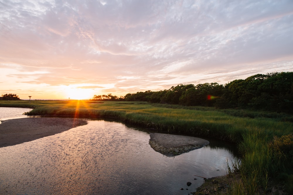 the sun is setting over a small river