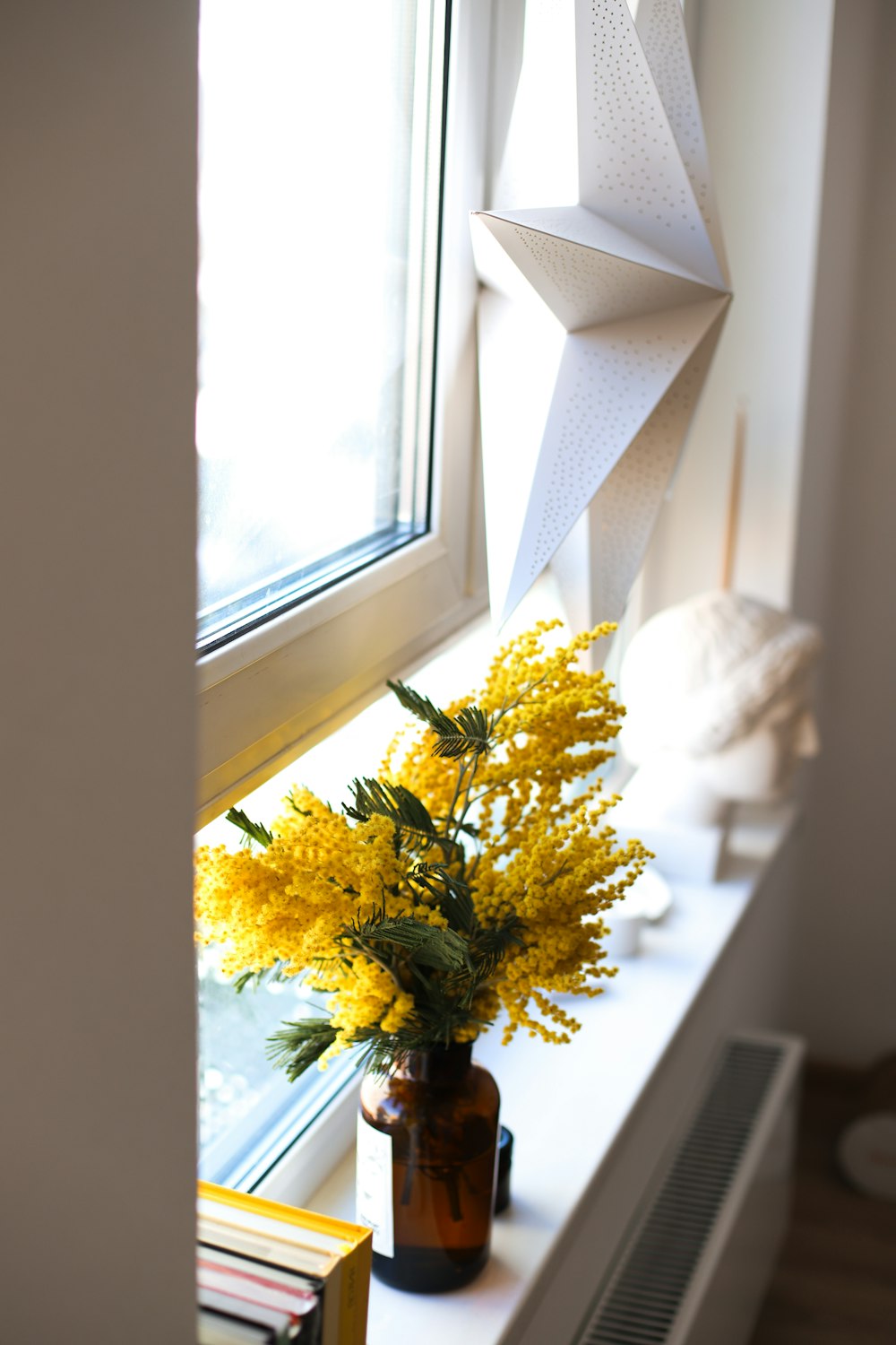 um vaso cheio de flores amarelas sentado no parapeito de uma janela