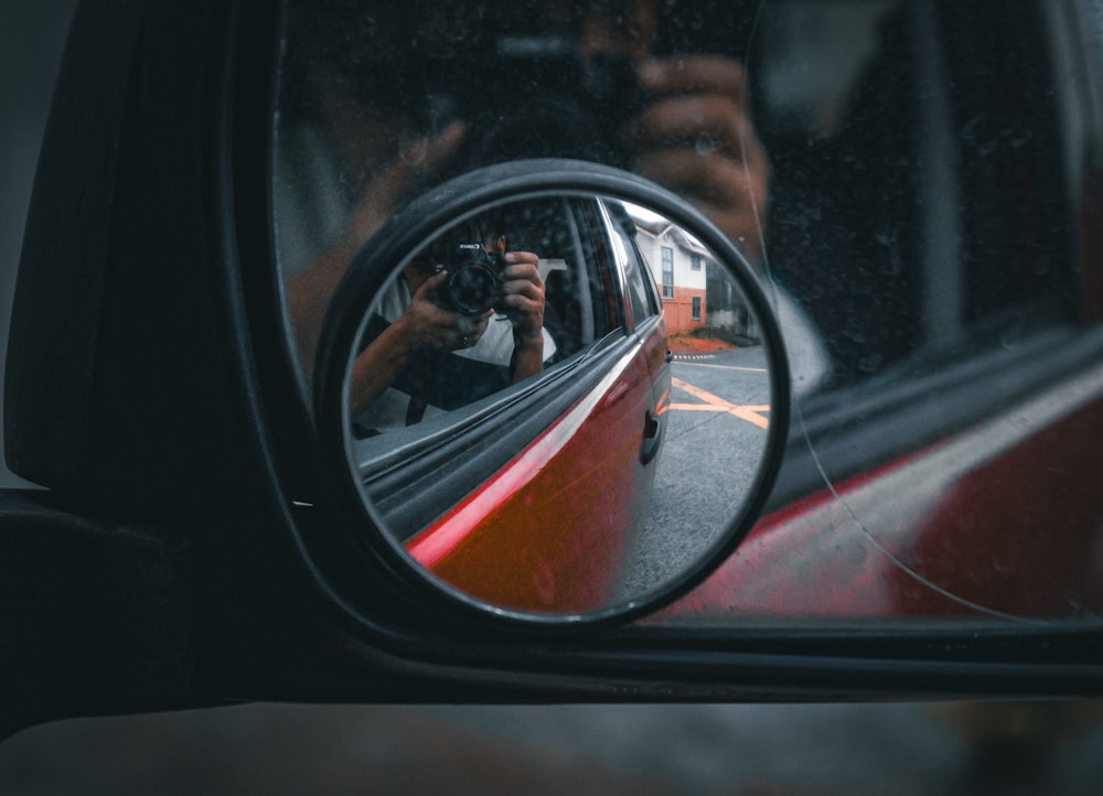 a woman taking a picture of herself in the side mirror of a car