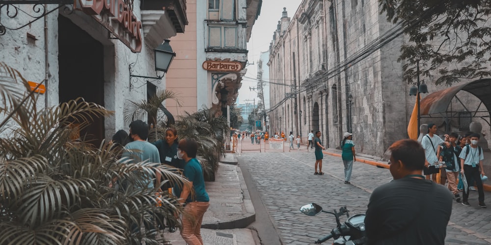 a group of people walking down a street next to tall buildings