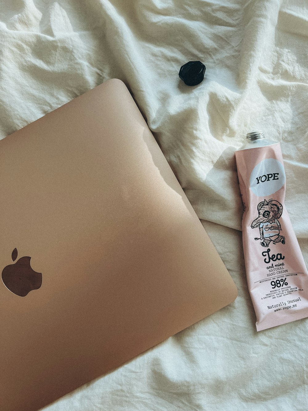 a laptop and a tube of toothpaste on a bed