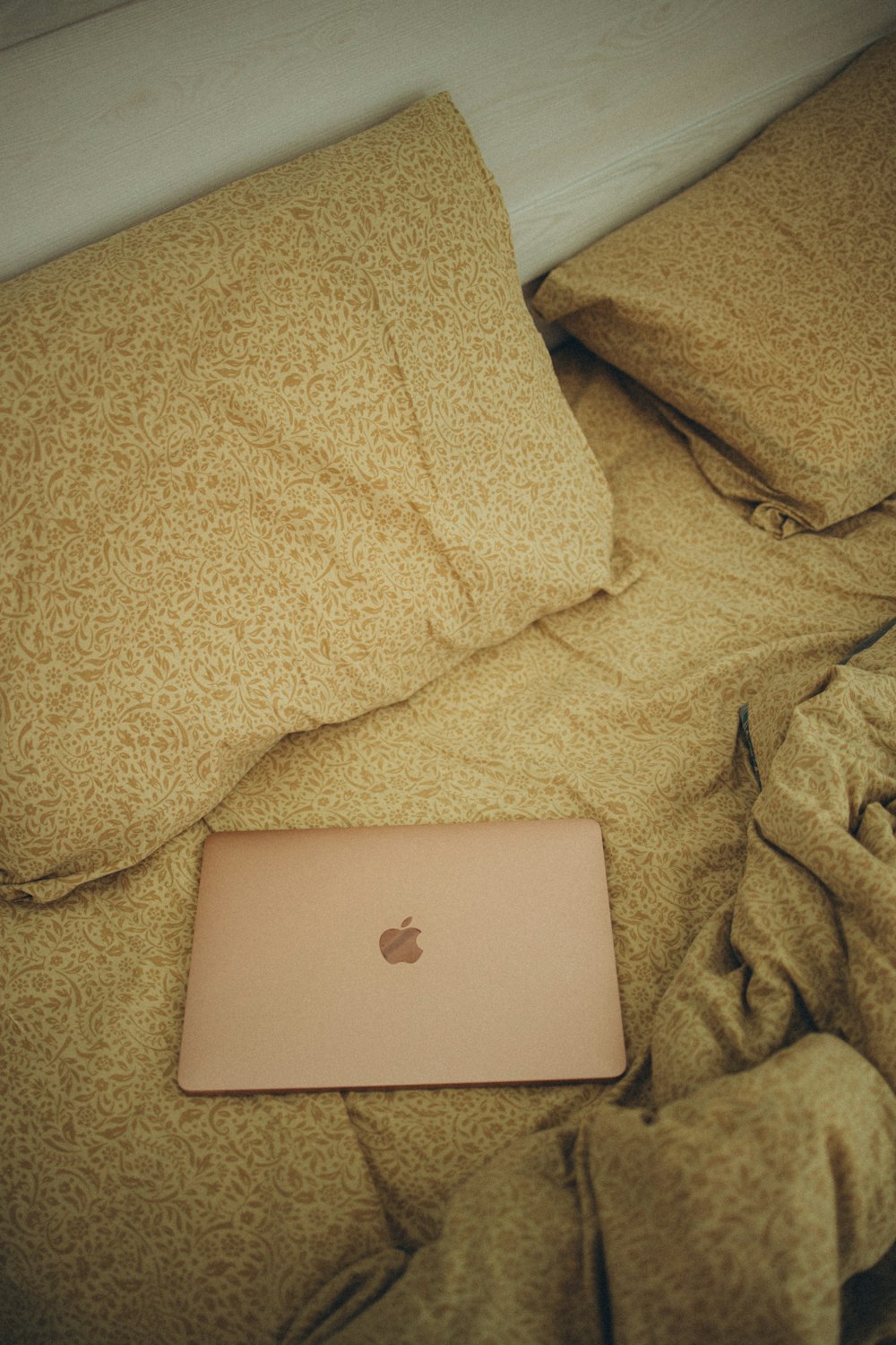 an apple laptop sitting on top of a bed