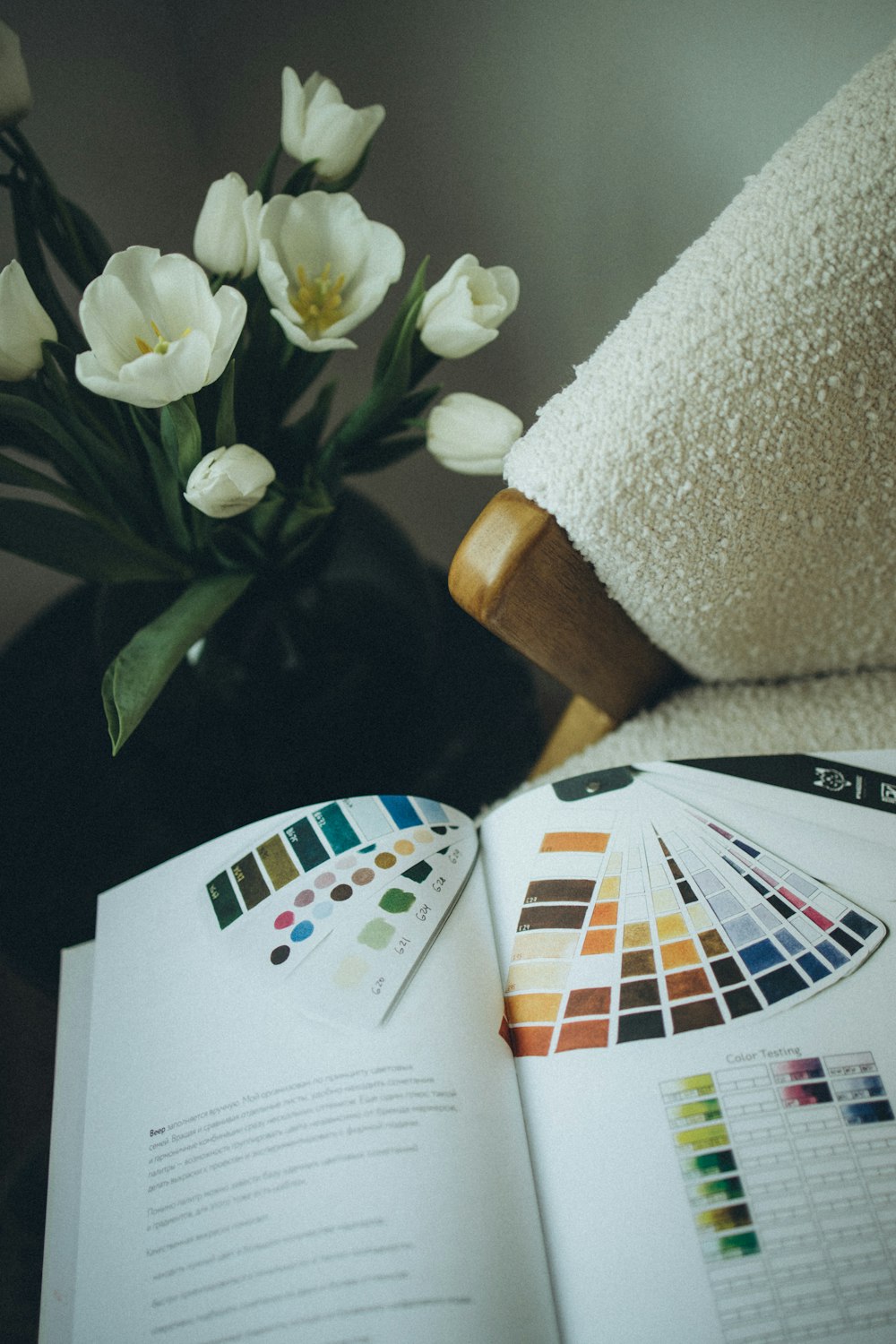 a book opened to a color guide next to a vase of flowers