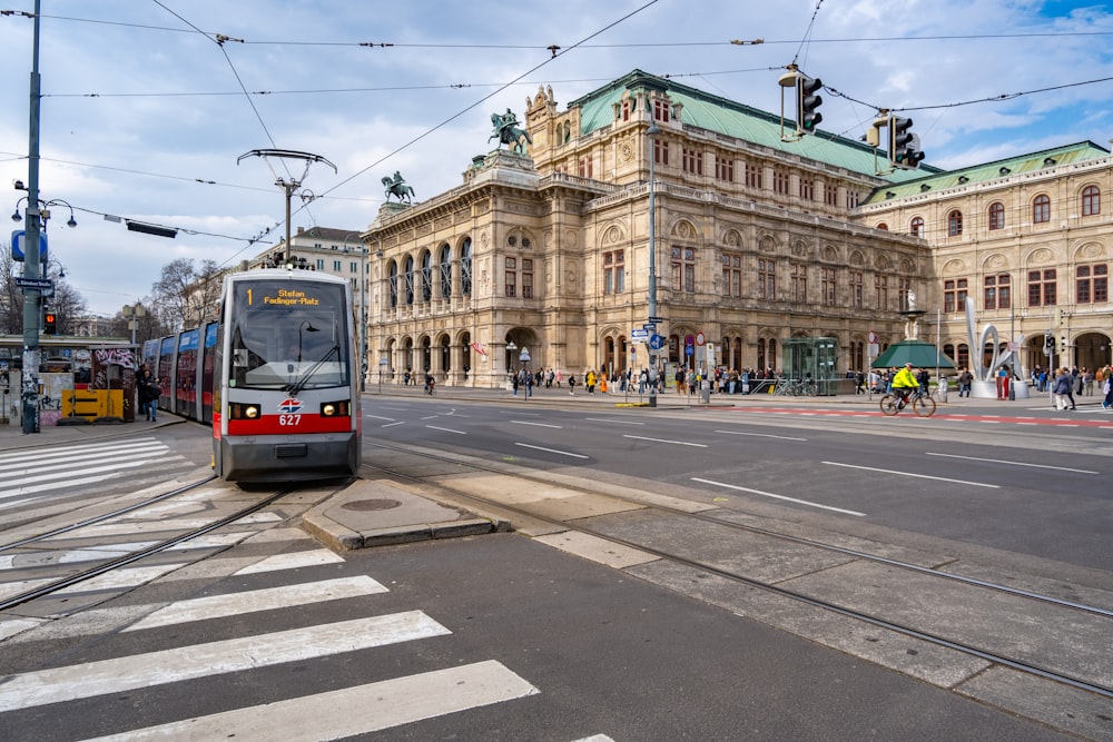 a train on the tracks in front of a large building