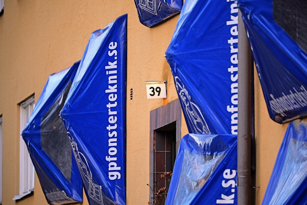 eine Gruppe blauer Regenschirme, die an der Seite eines Gebäudes sitzen