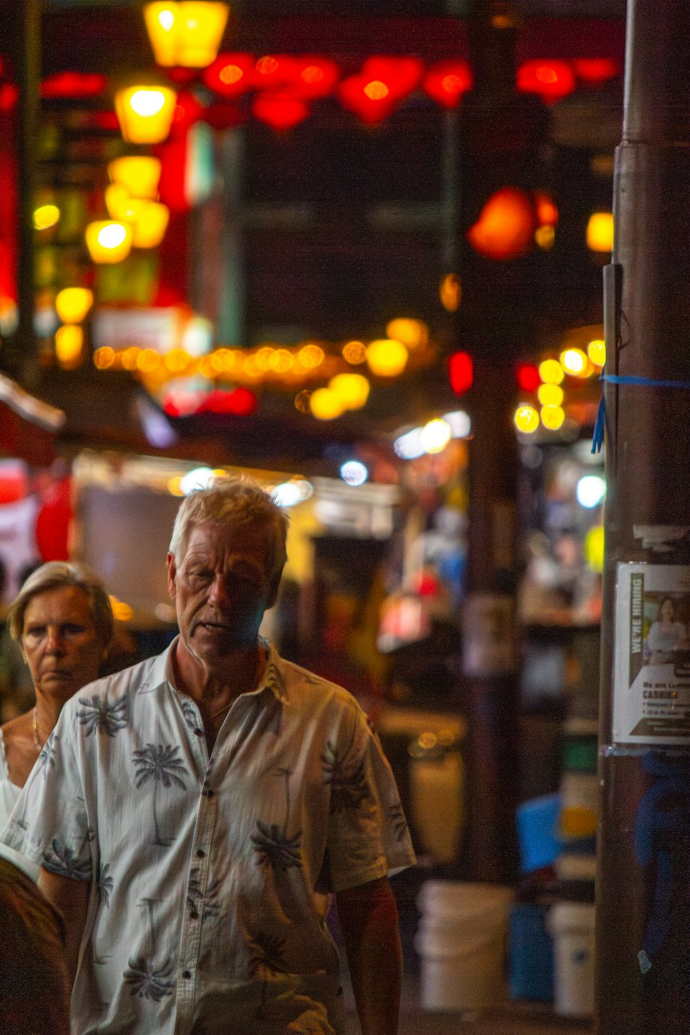 a man and woman walking down a street at night