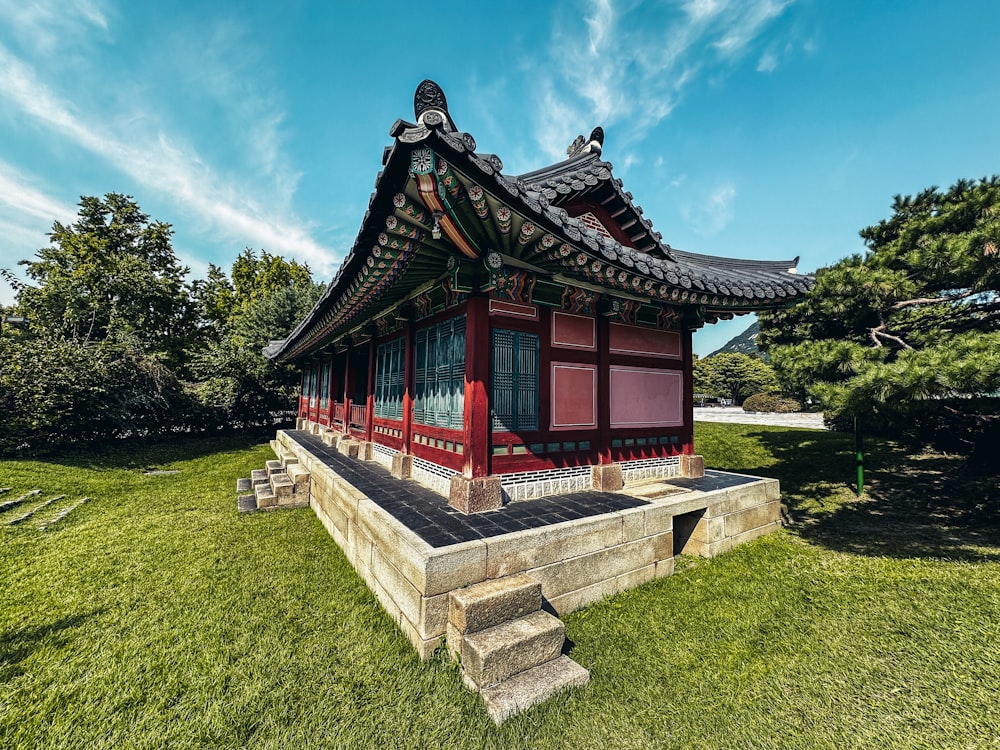 a small red building sitting on top of a lush green field