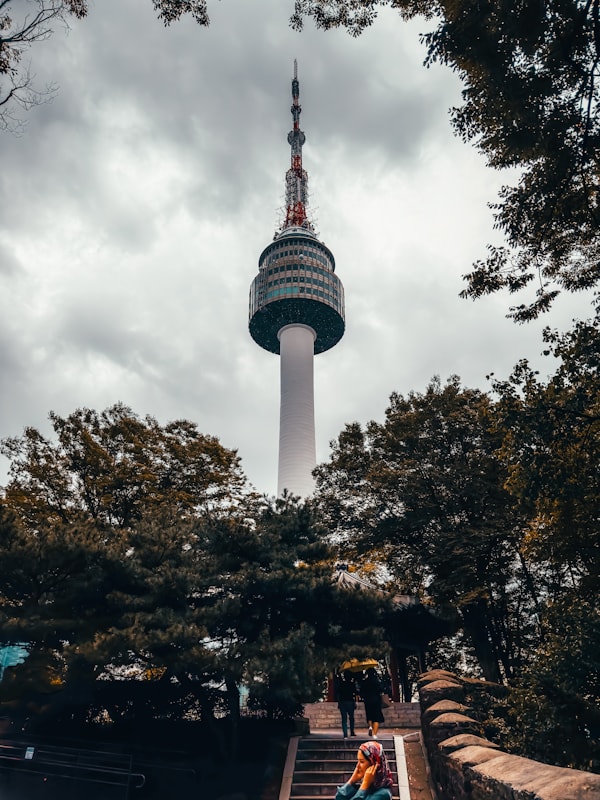 a person sitting on a bench in front of a tall tower