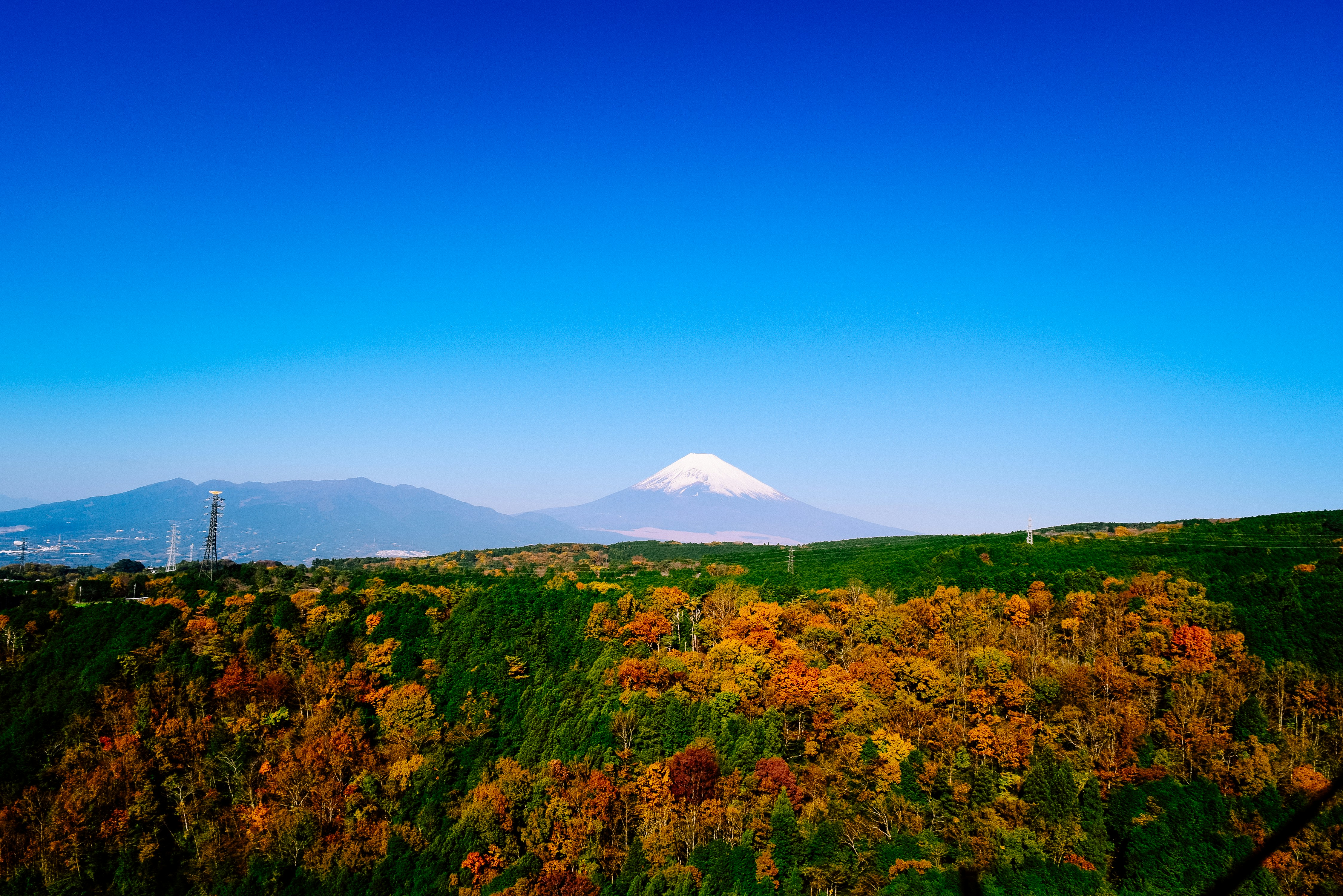 a view of a mountain in the distance with trees in the foreground, Mt.Fuji from Mishima Skywalk.