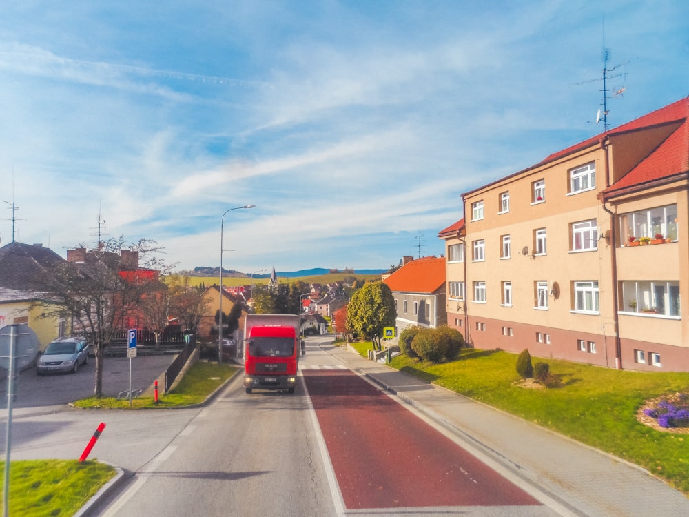 a red truck driving down a street next to tall buildings