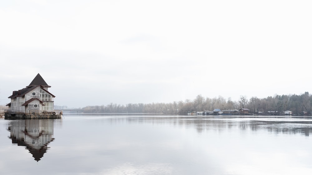 a house sitting on top of a lake next to a forest