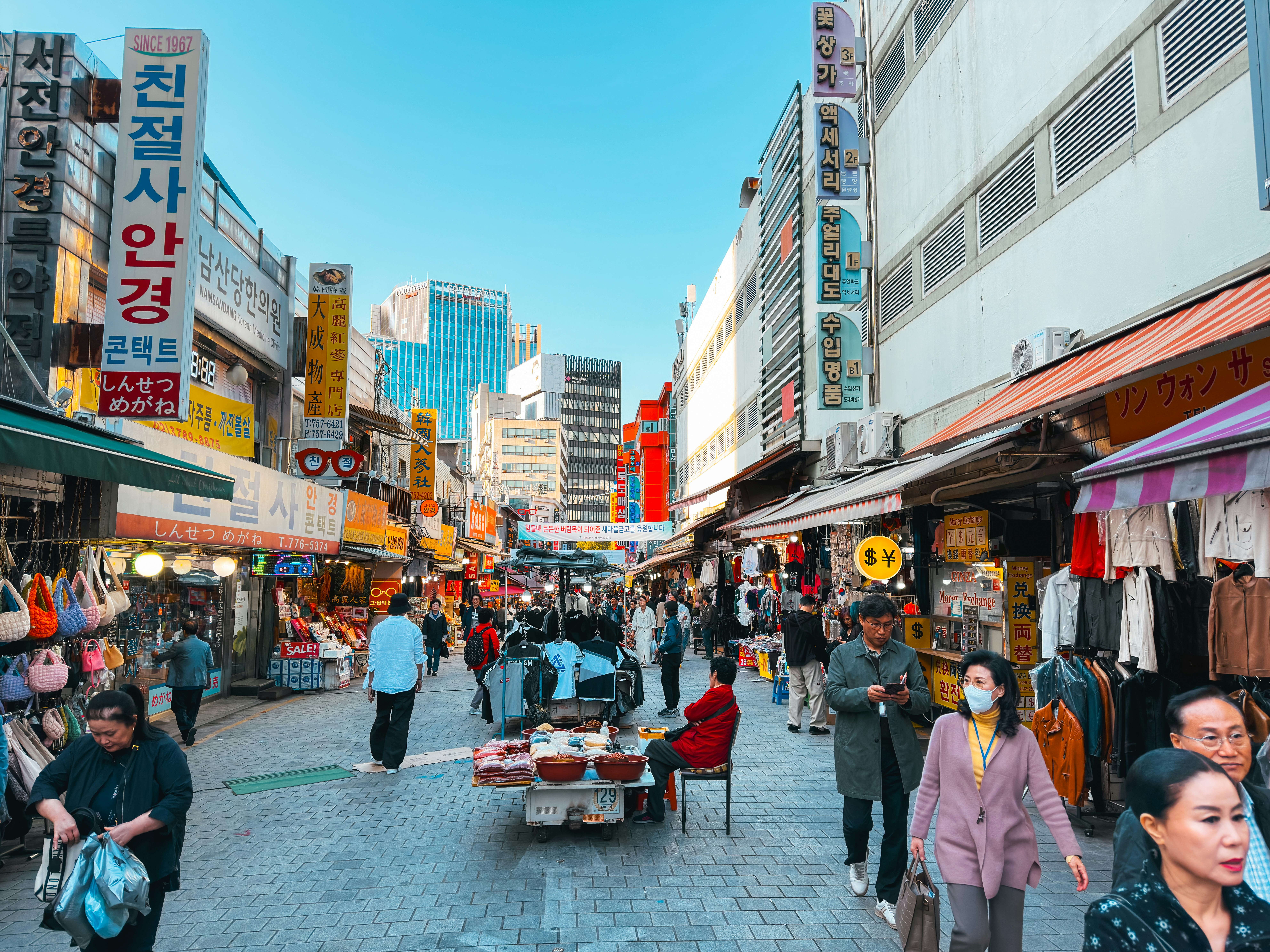 a group of people walking down a street next to tall buildings