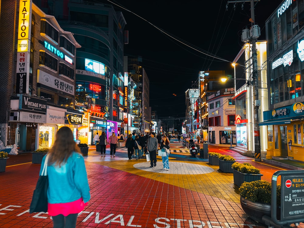 a group of people walking down a street at night