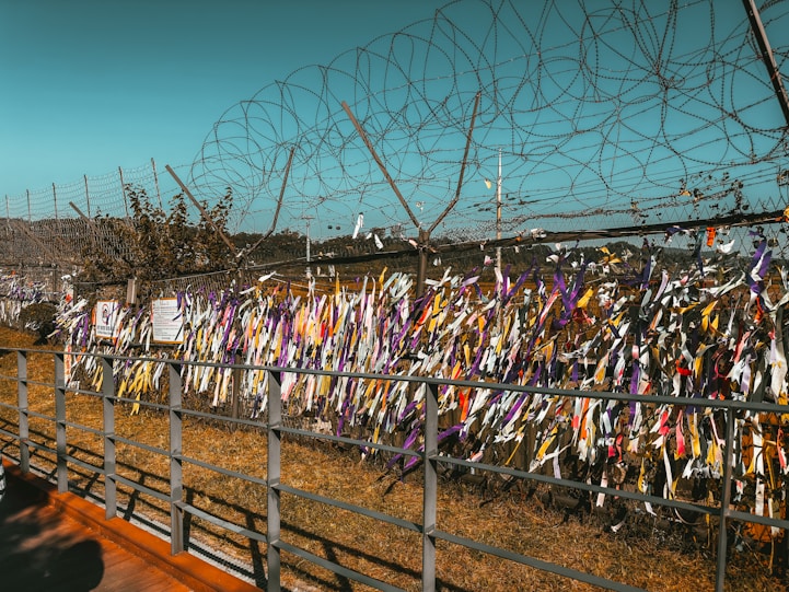 DMZ Tours: Understanding the Heart of the Korean Peninsula a fence covered in many  colored ribbons