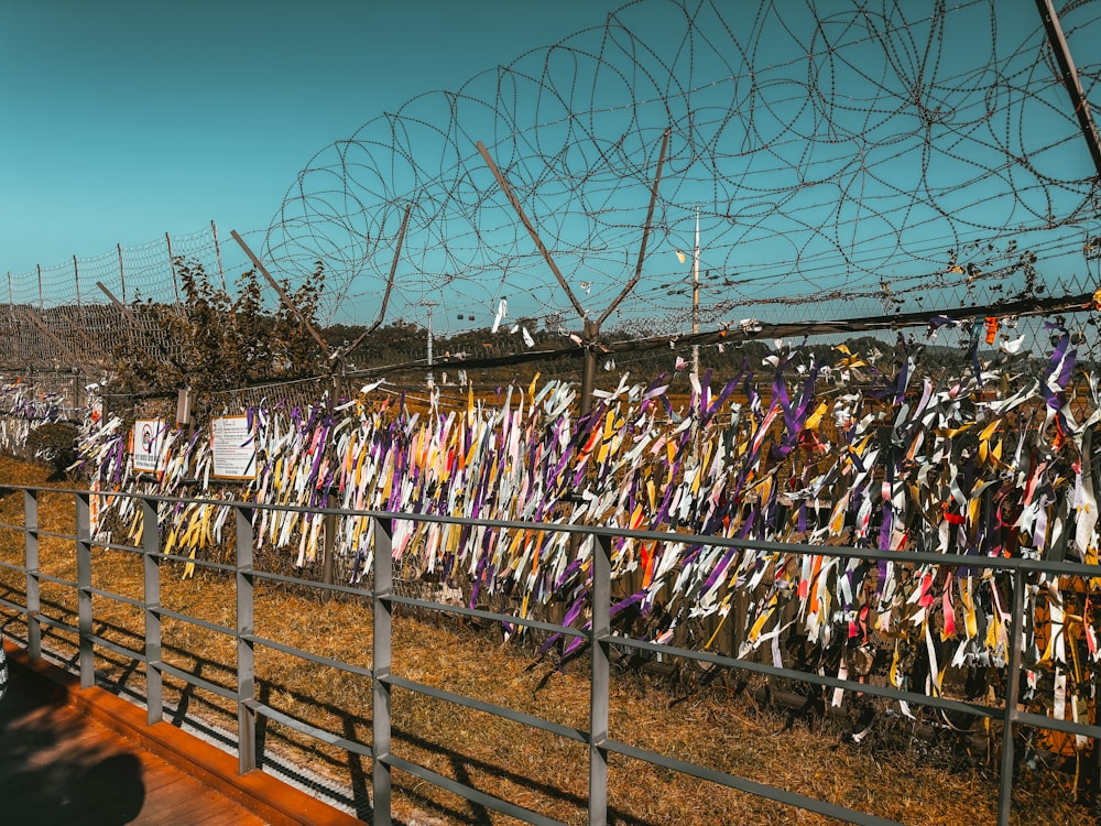 a fence covered in many different colored ribbons