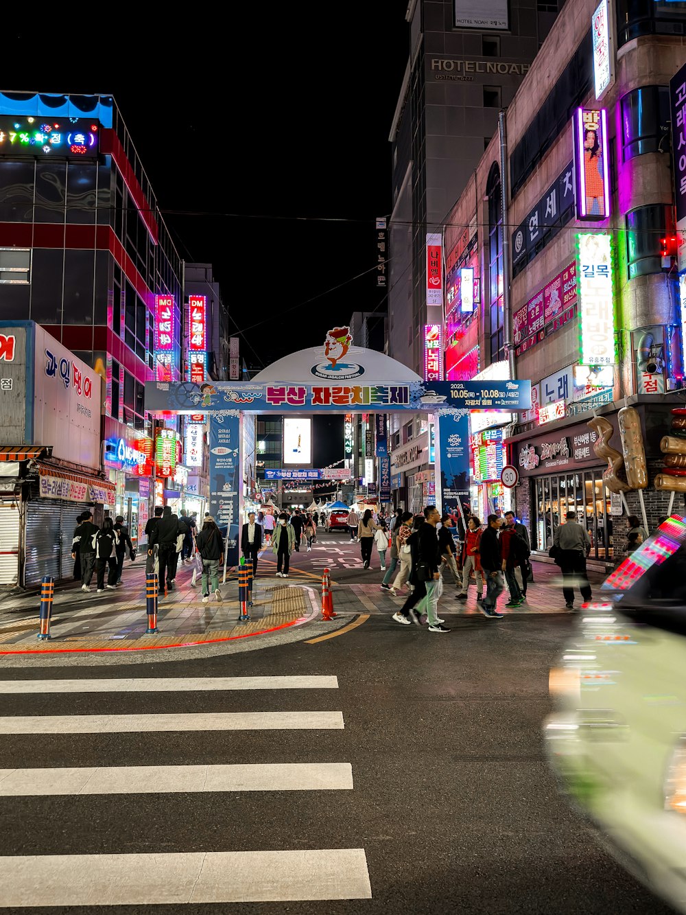 a busy city street at night with people crossing the street