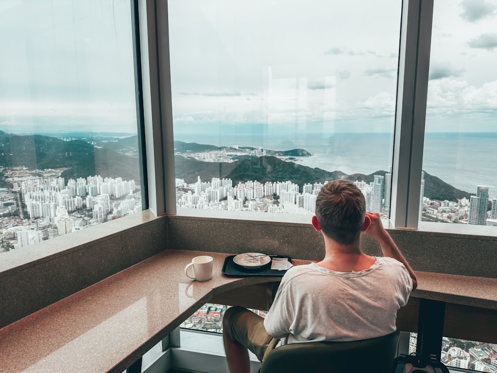 a man sitting at a desk looking out a window