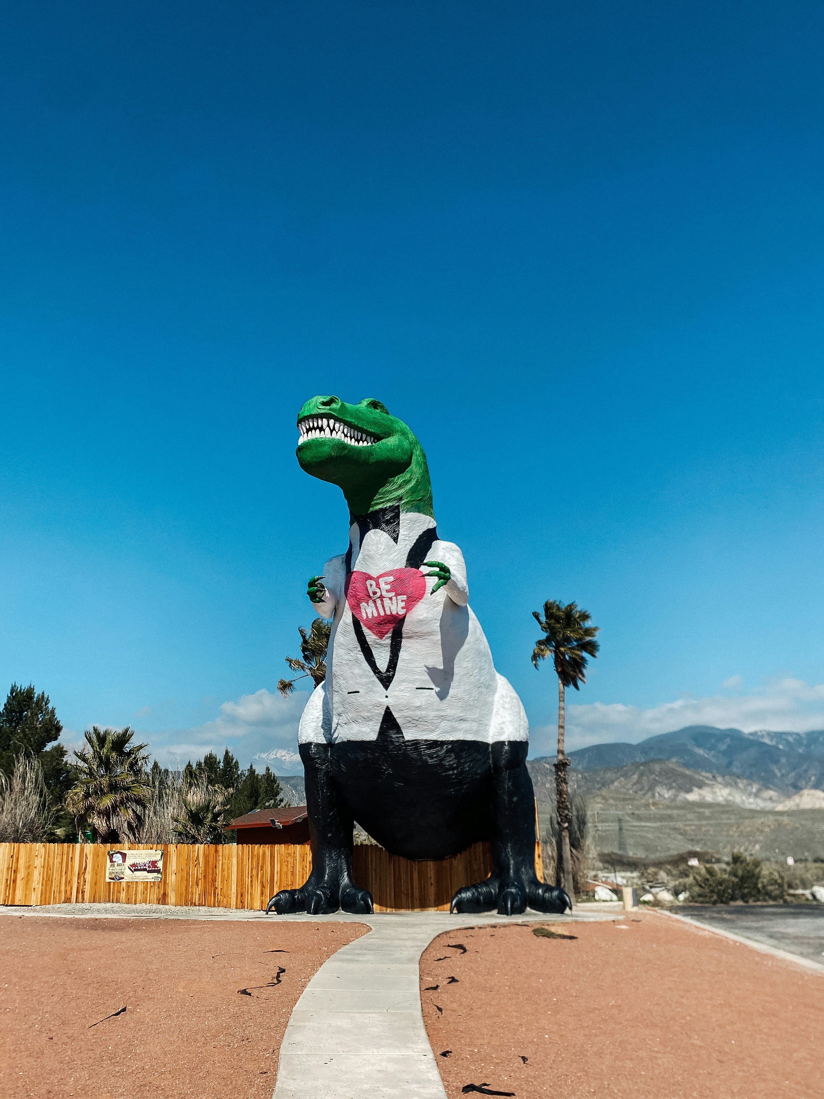 dinosaurus tiup besar duduk di atas trotoar