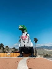 a large inflatable dinosaur sitting on top of a sidewalk