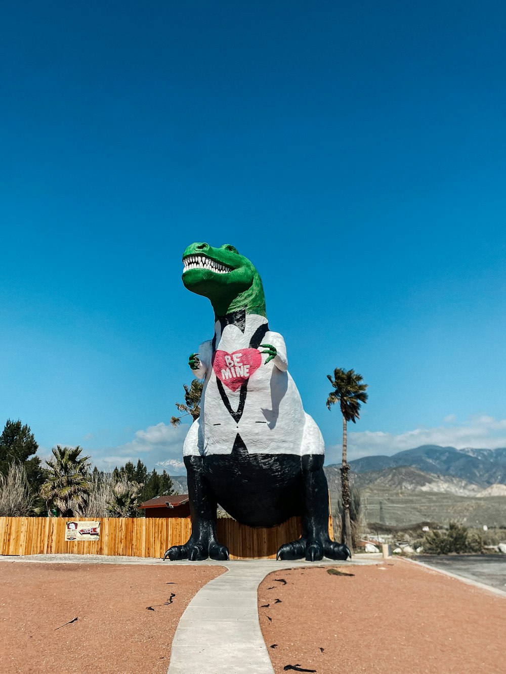 a large inflatable dinosaur sitting on top of a sidewalk