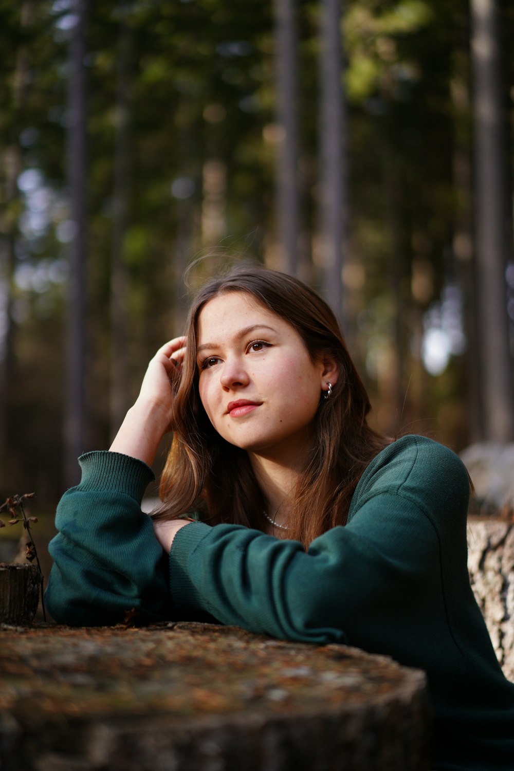 a woman sitting on a log in the woods