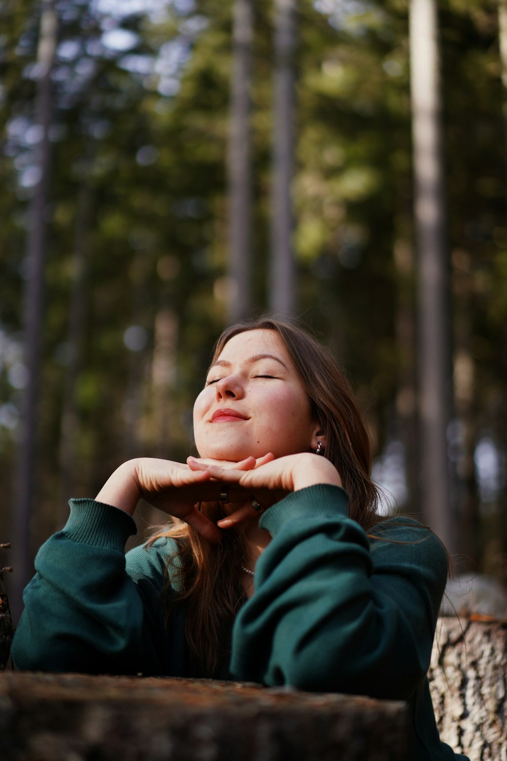 a woman sitting in the woods with her eyes closed