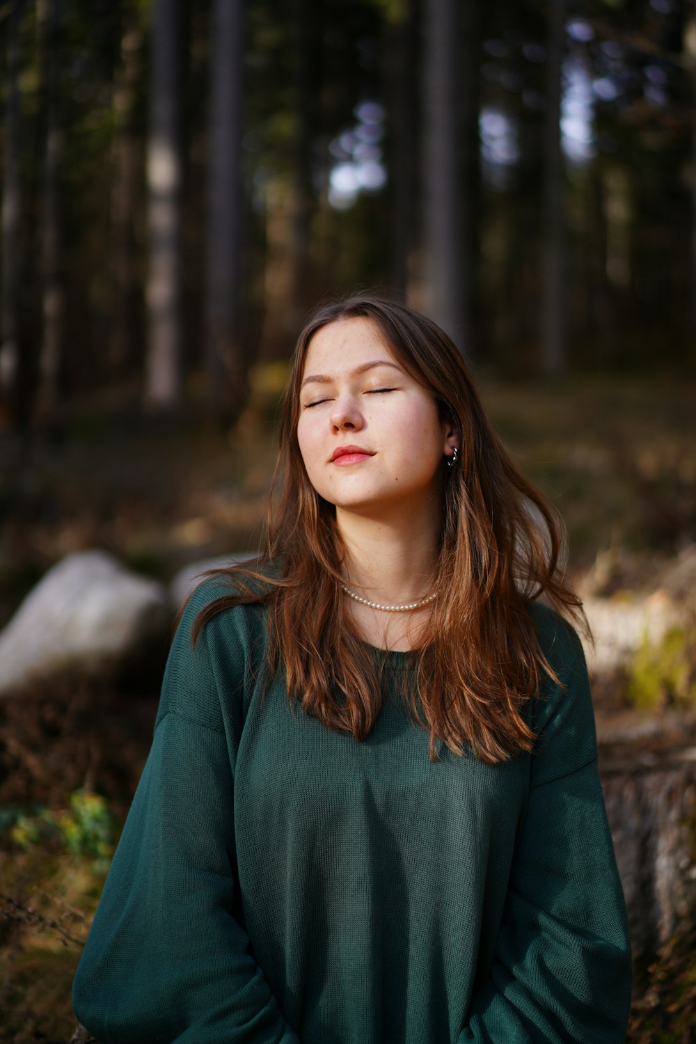 a woman with her eyes closed standing in a forest