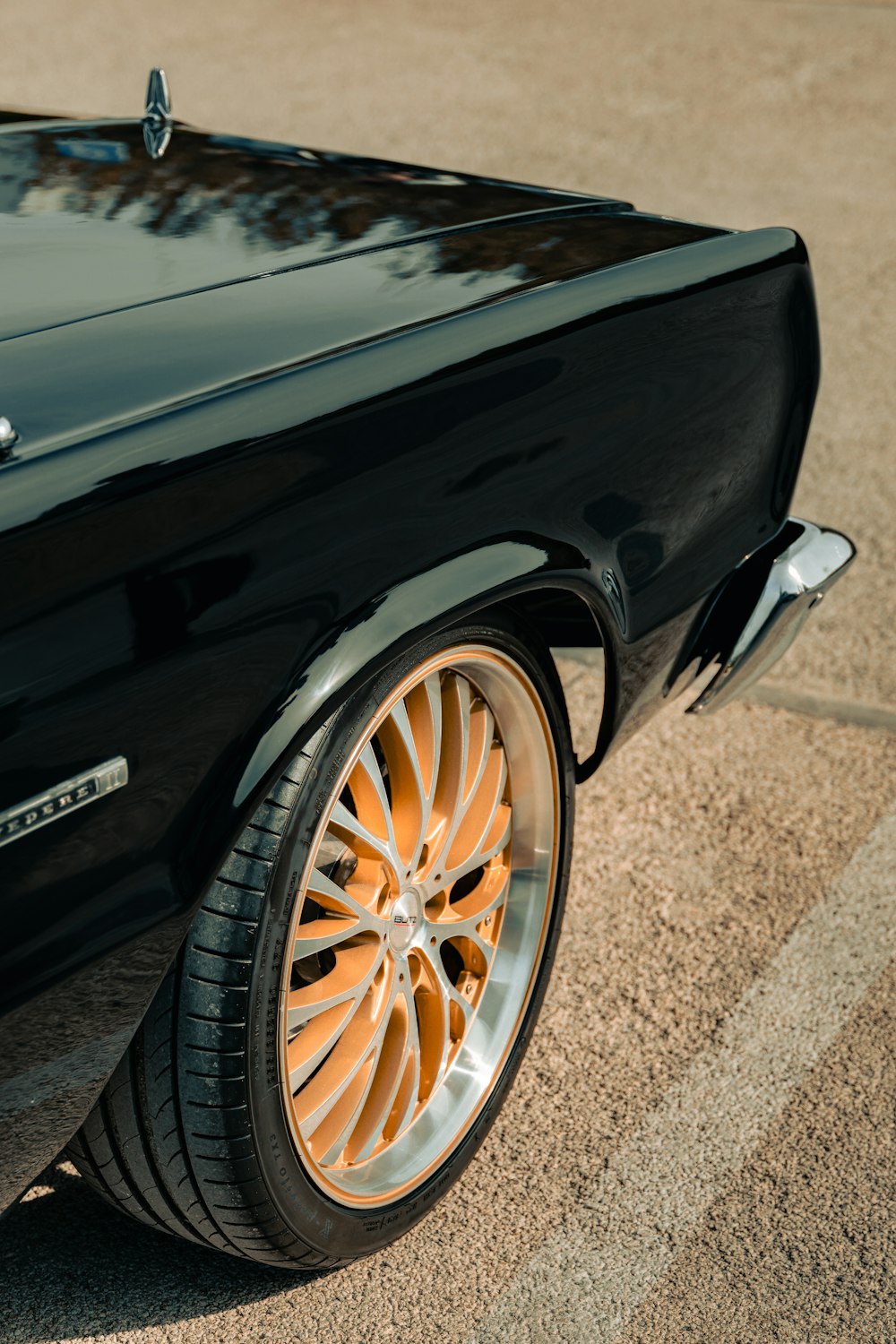 a close up of a black car parked in a parking lot