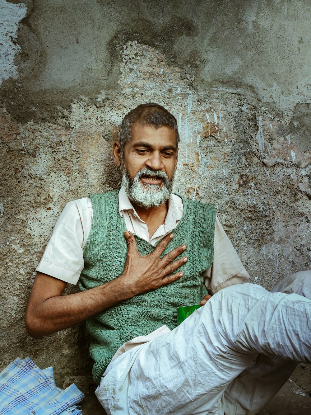 a man sitting against a wall with his hands crossed