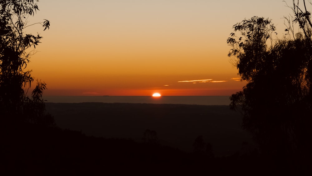 the sun is setting over the horizon of a valley