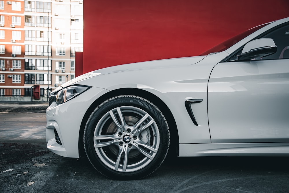 a white car parked in front of a red wall