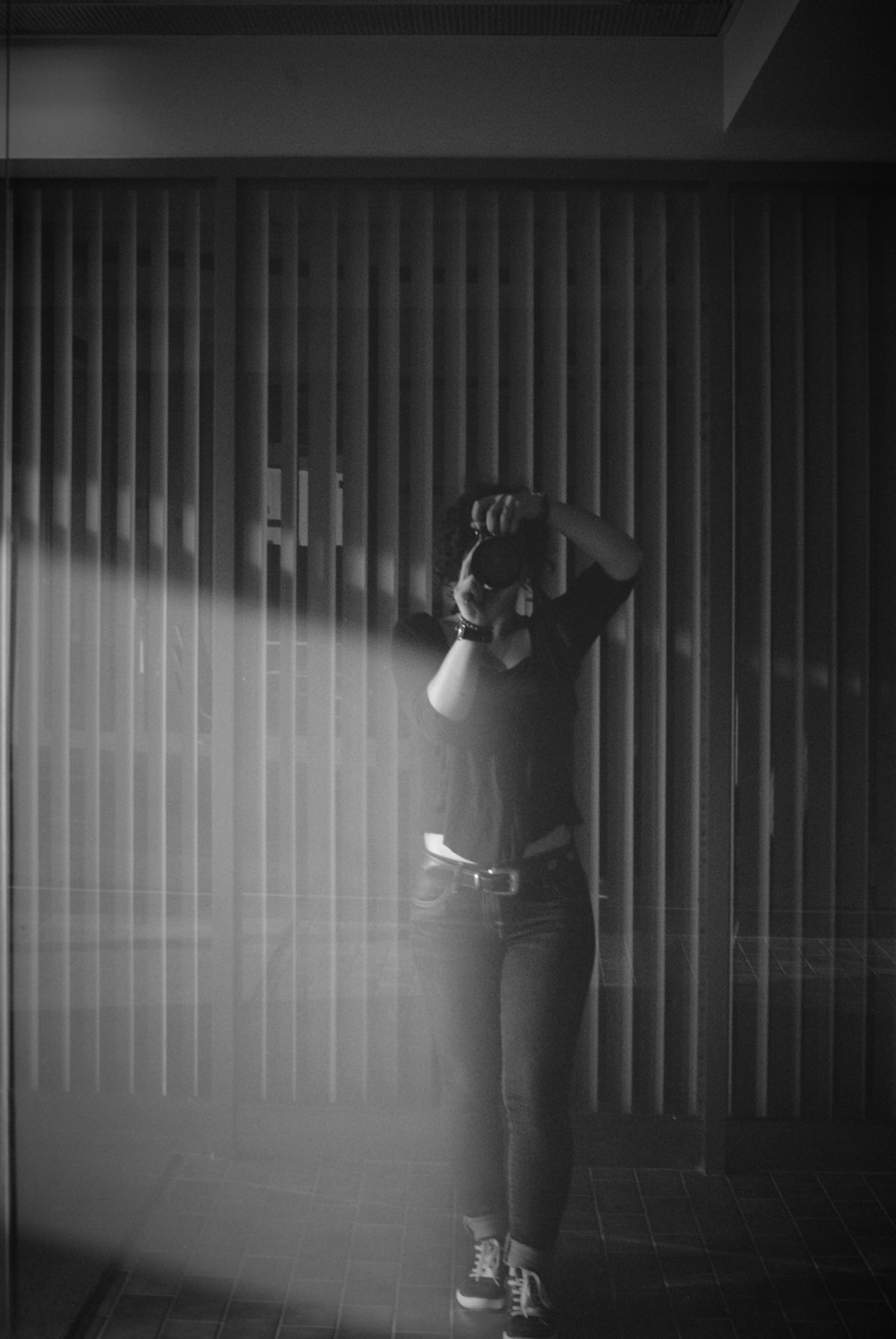 a woman standing in front of a wall holding a cell phone