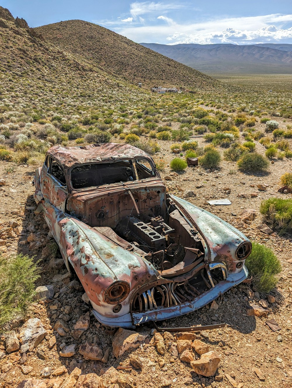 an old rusty car sitting in the middle of the desert