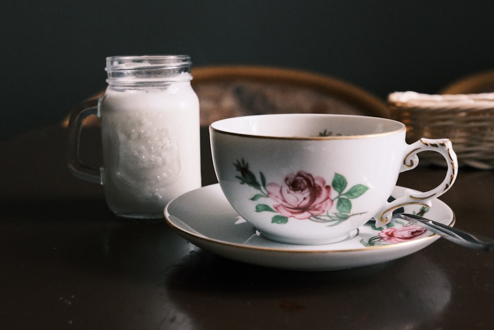 eine Teetasse und Untertasse auf einem Tisch neben einem Glas Zucker