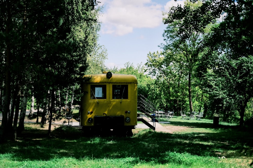 a yellow caboose sitting in the middle of a forest