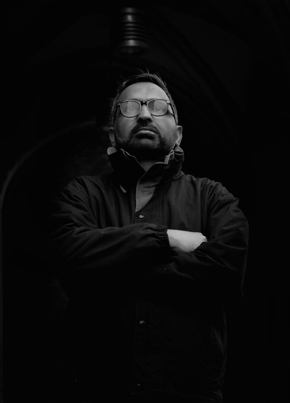 a man with his arms crossed in a black and white photo