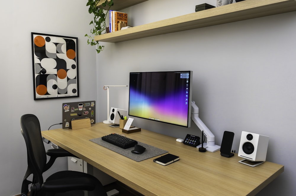 a desk with a computer monitor, keyboard and speakers