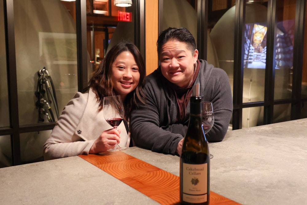 a man and a woman sitting at a table with a glass of wine