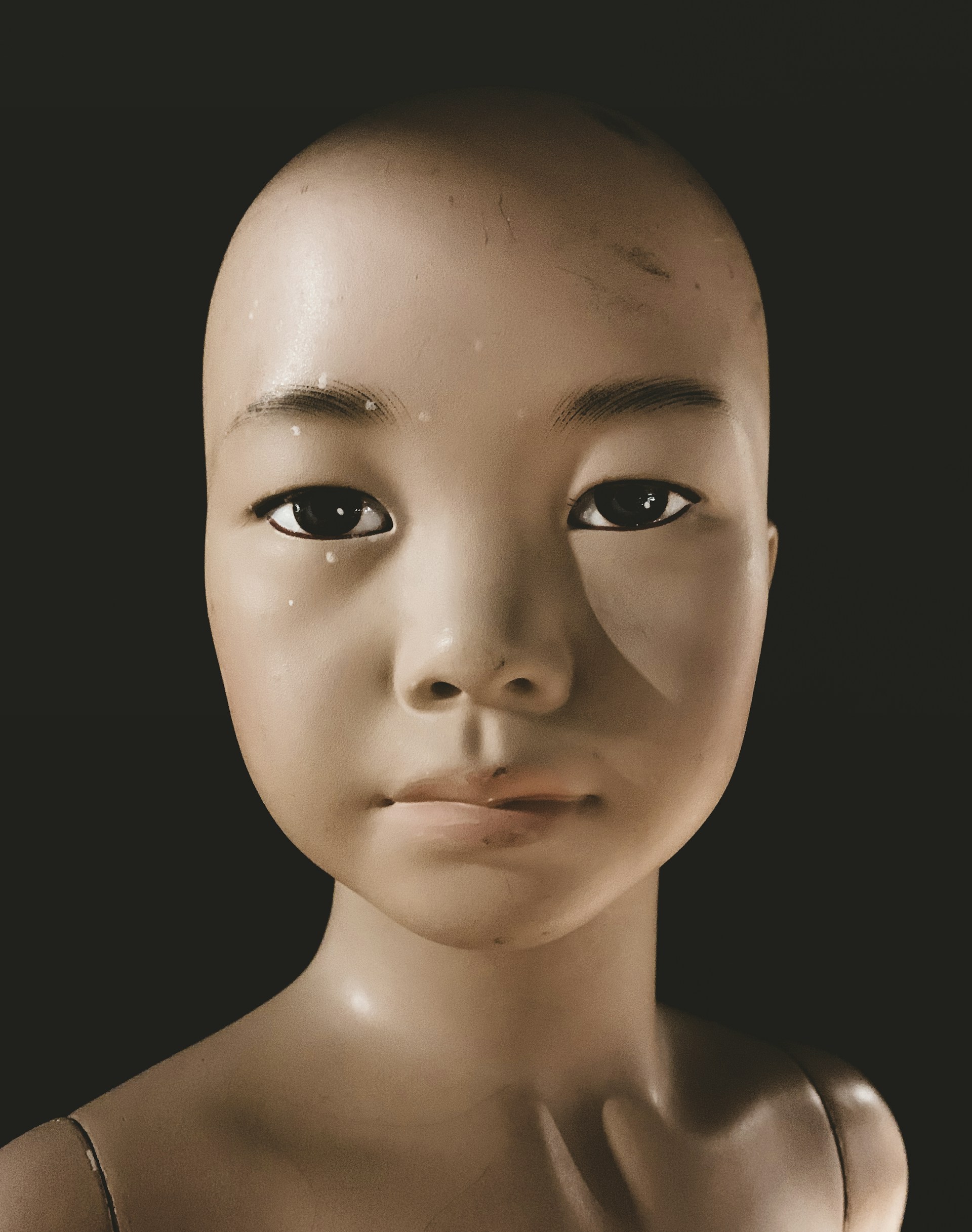 a white mannequin head with a black background