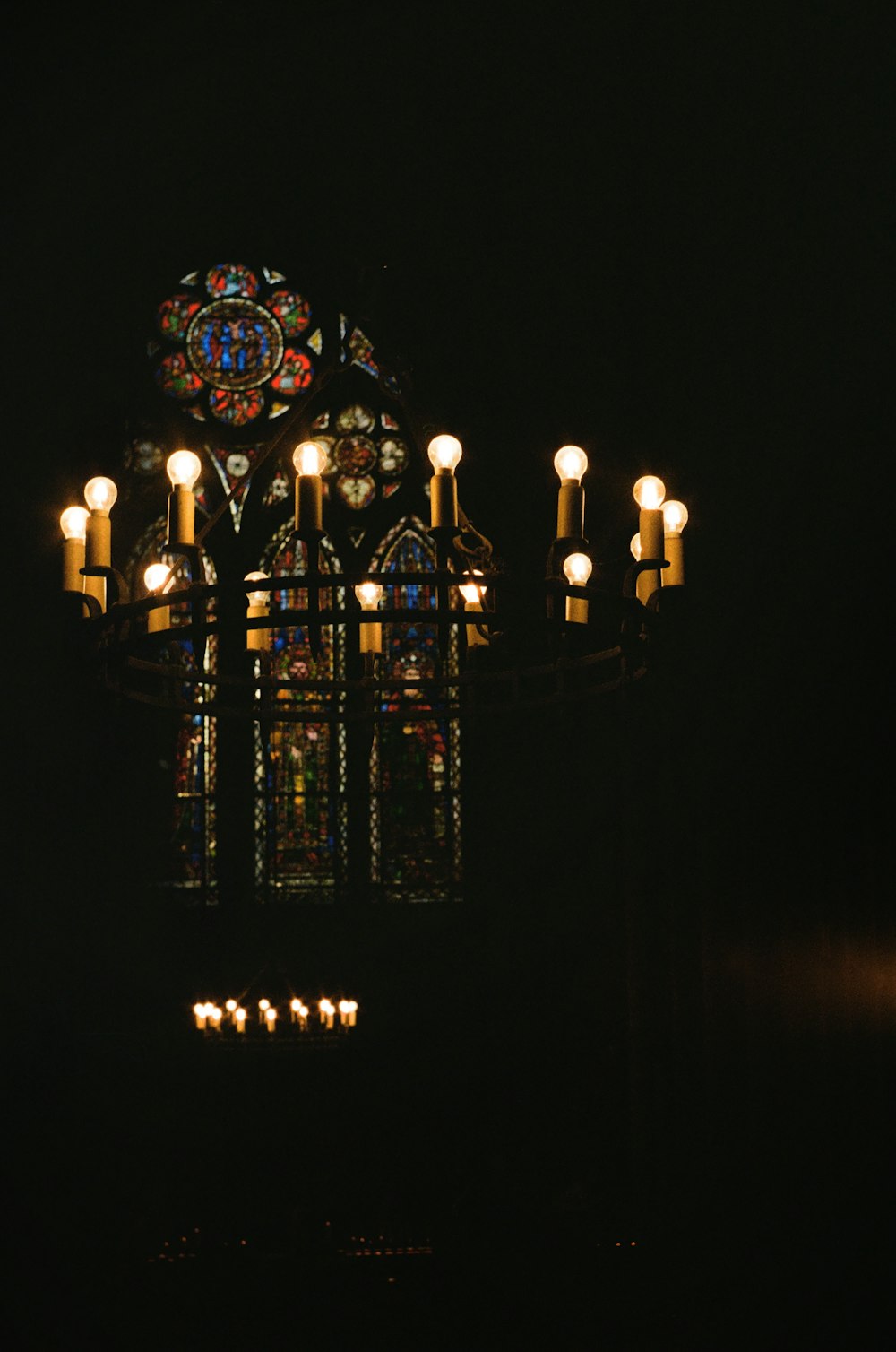 a lit chandelier with a stained glass window in the background