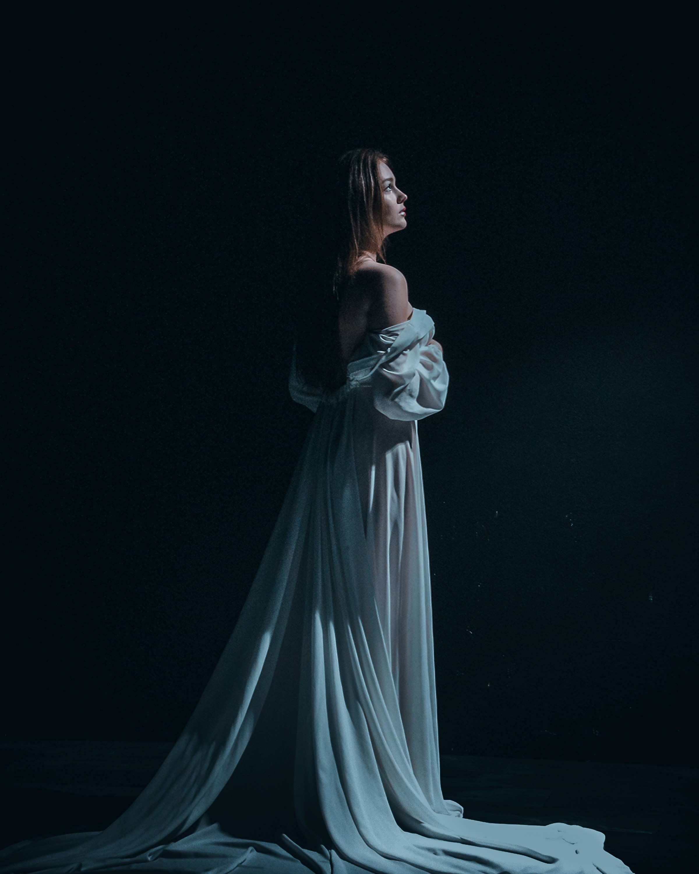Eine Frau in einem weißen Kleid steht im Dunkeln