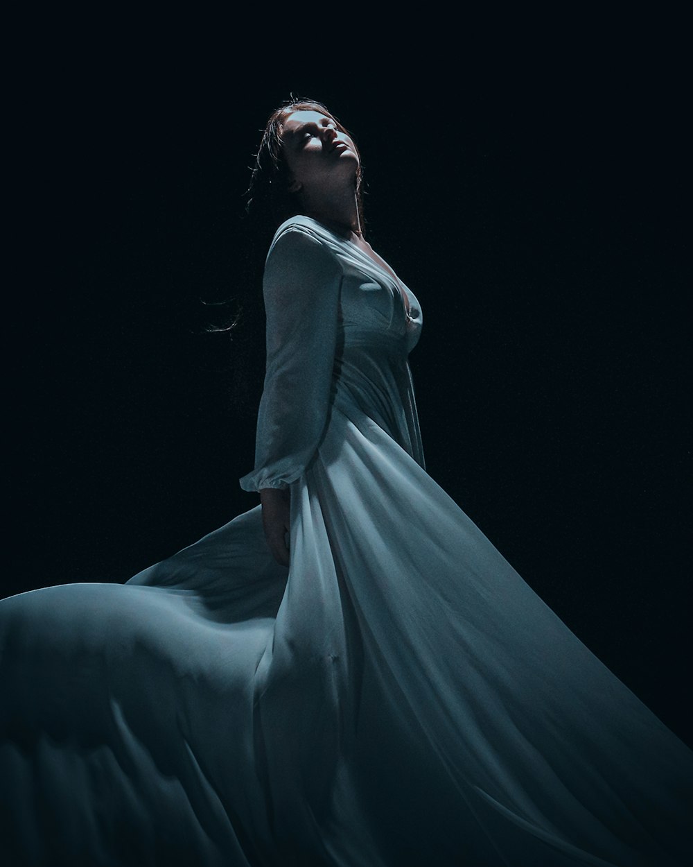 a woman in a white dress standing in the dark