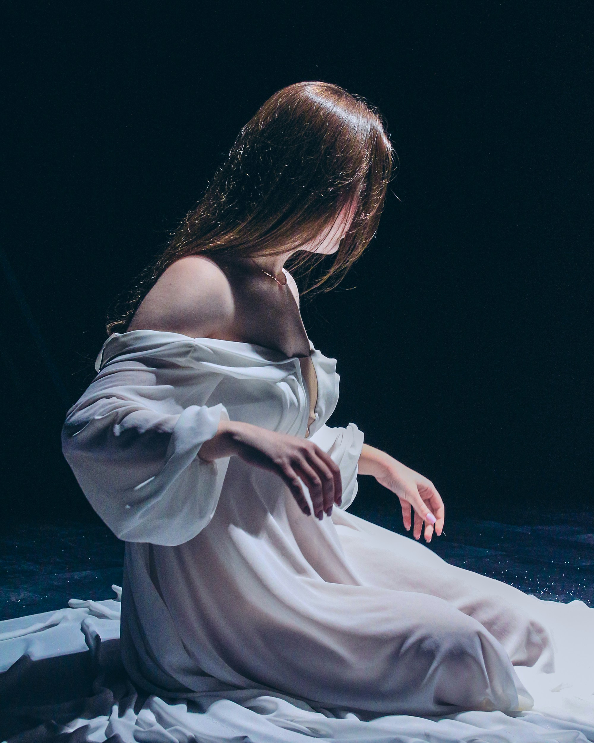 a woman in a white dress sitting on the ground