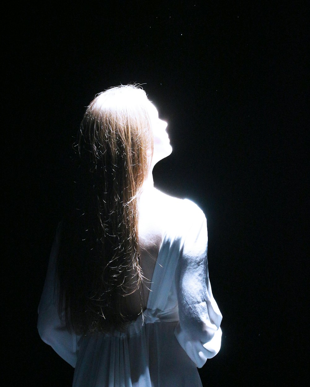 une femme aux cheveux longs debout dans l’obscurité