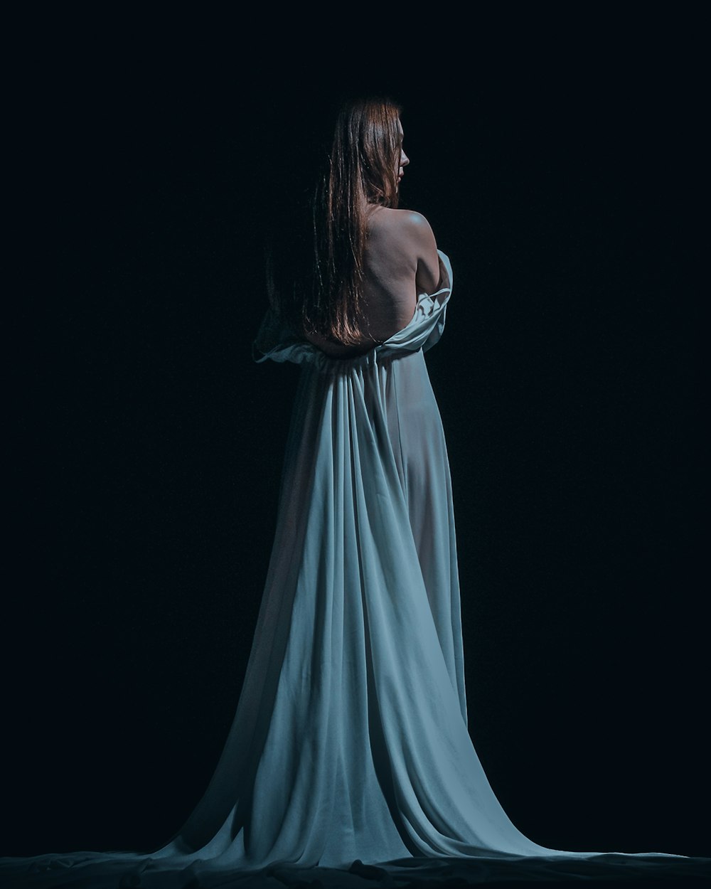 a woman in a blue dress standing in the dark