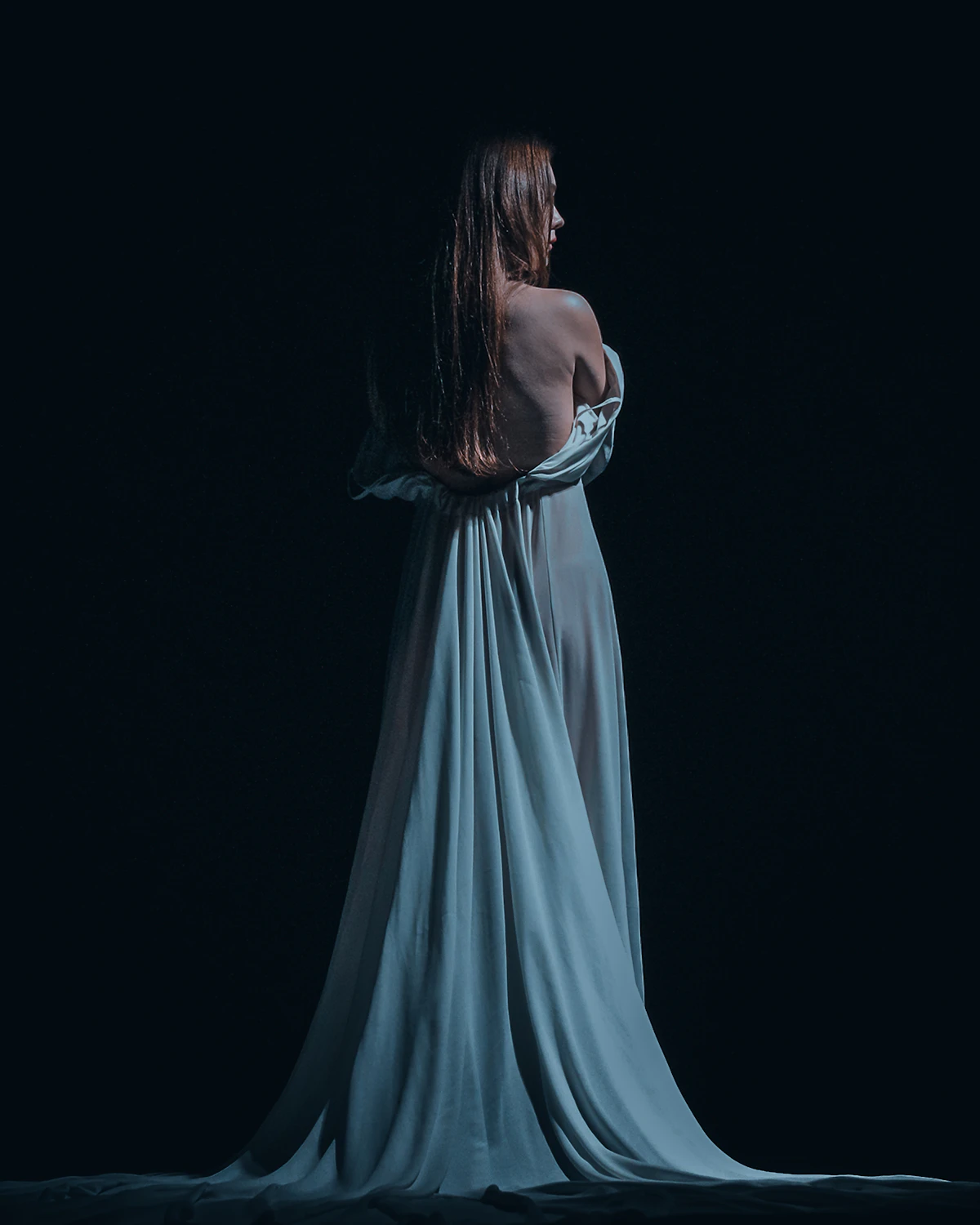 Woman in an elegant blue evening gown in dramatic lighting