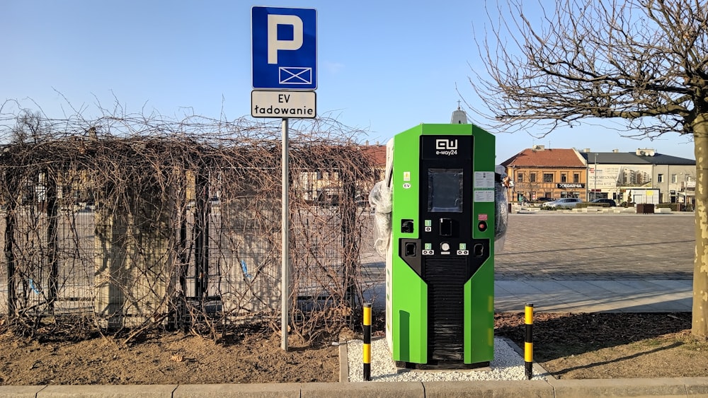 a green parking meter next to a parking sign