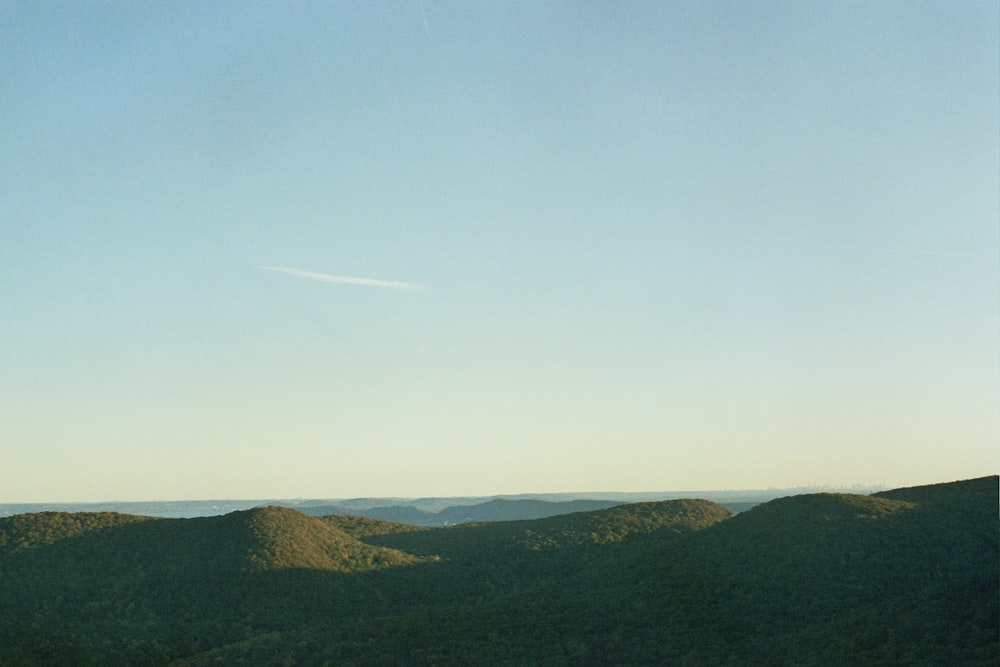 a plane flying over a lush green hillside