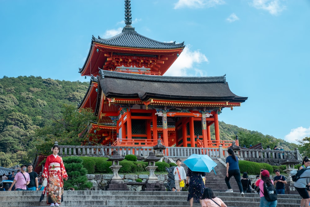 a group of people with umbrellas standing in front of a pagoda